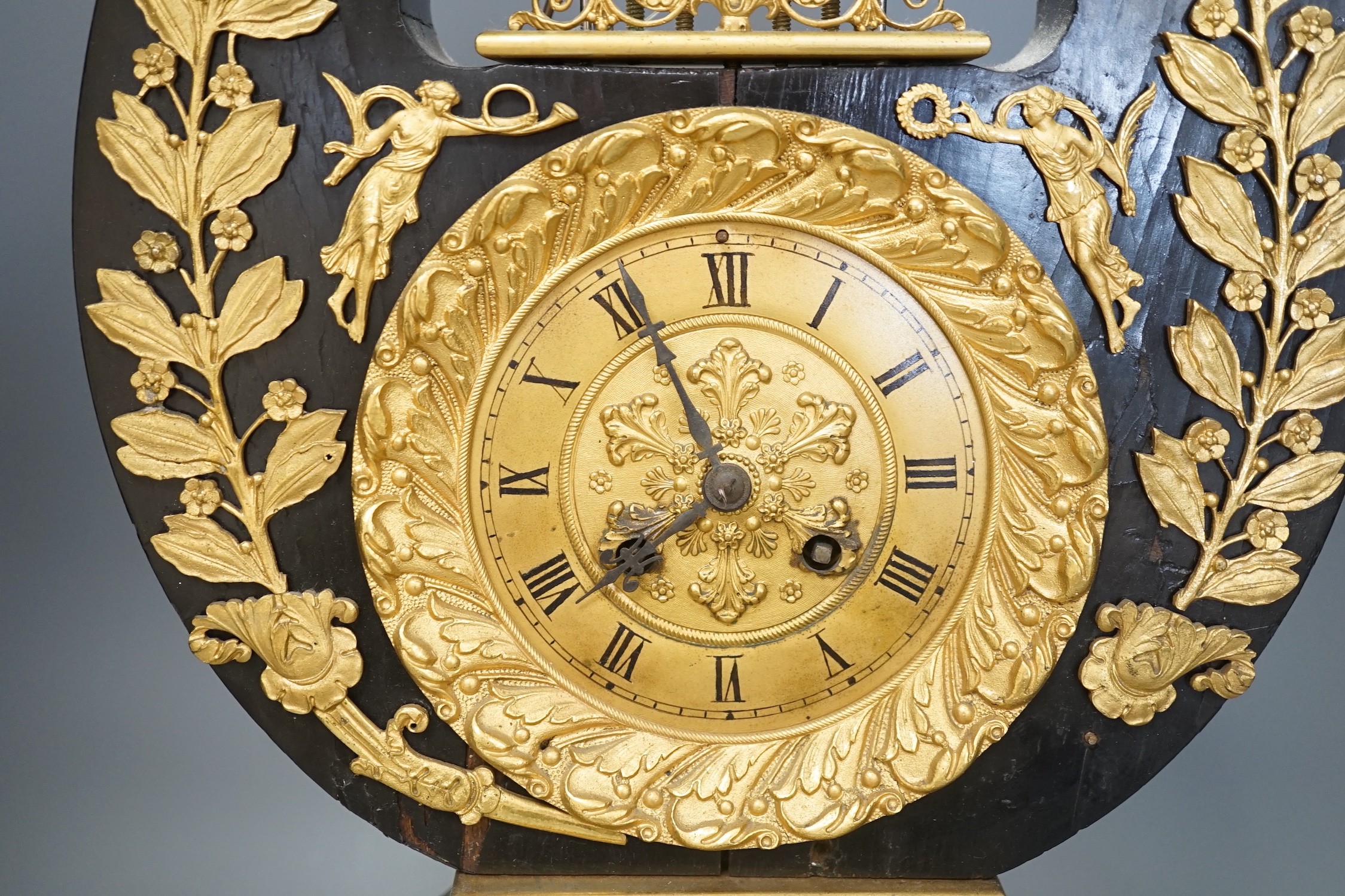 A 19th century French black lyre shaped clock, with gilt leaf decoration on scroll feet, 57cm tall